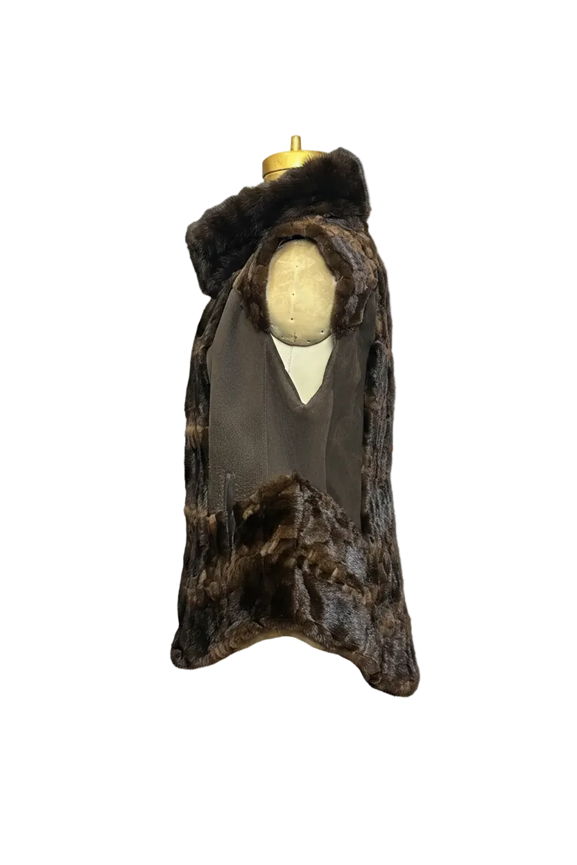 A dark brown fur cape vest with a wide collar and a V-shaped front, displayed on a cream-colored mannequin torso with a gold neck cap against a plain white background.