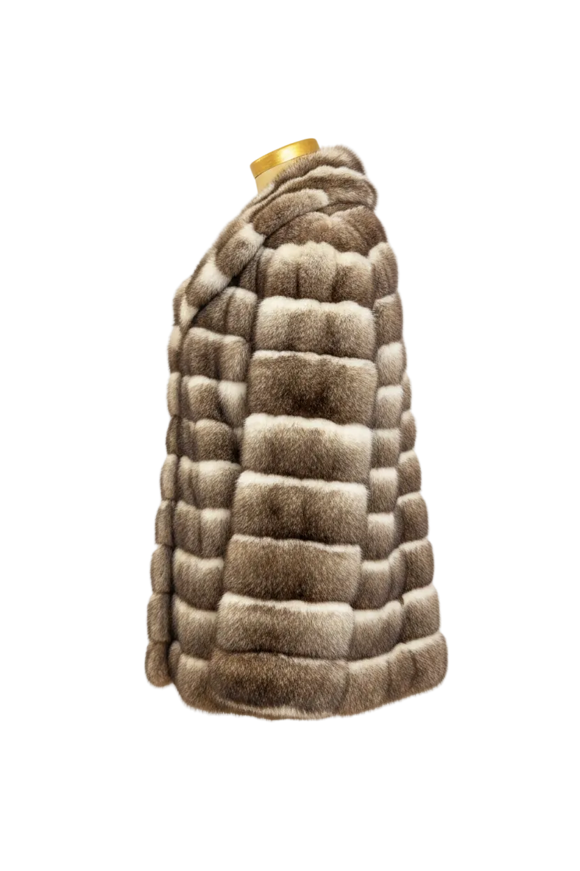 A cropped fur coat shown from the side on a mannequin, featuring horizontal striped patches in shades of brown, beige, and gray, with a gold mannequin neck visible at the top.