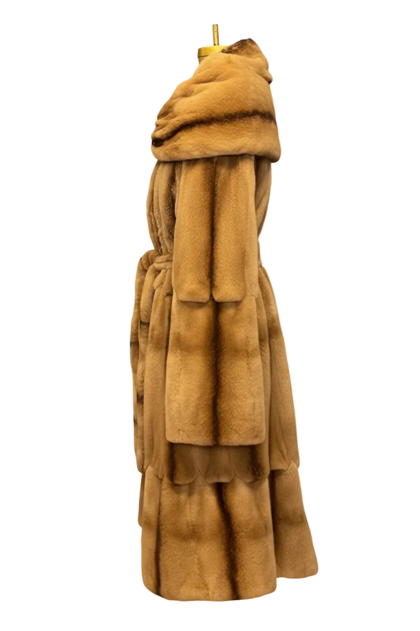 A long tan-brown fur coat displayed on a mannequin against a gray-and-white checkered background.