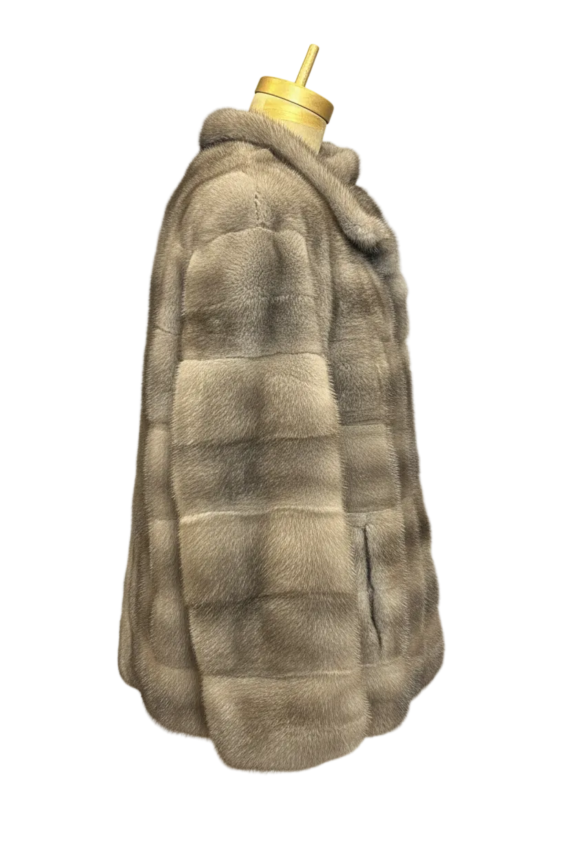 A side view of a plush, puffer-style faux fur jacket in a taupe-gray color, displayed on a mannequin torso with a gold neck cap against a checkered transparency background.