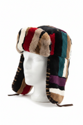 A multicolor patchwork faux fur and shearling trapper hat with ear flaps, displayed on a white mannequin head against a white background.