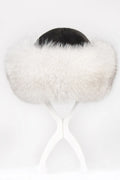 A white fur-trimmed winter hat with a black crown, displayed on a white stand against a white background.